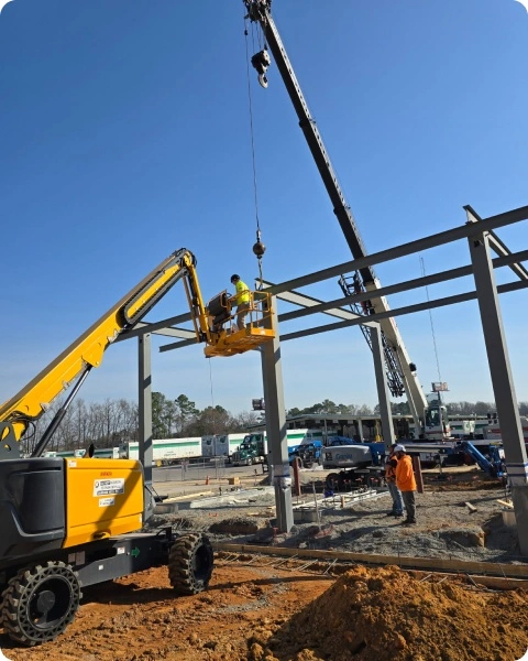 Construction workers using crane and lift at Heartland Building Group project site for steel framework