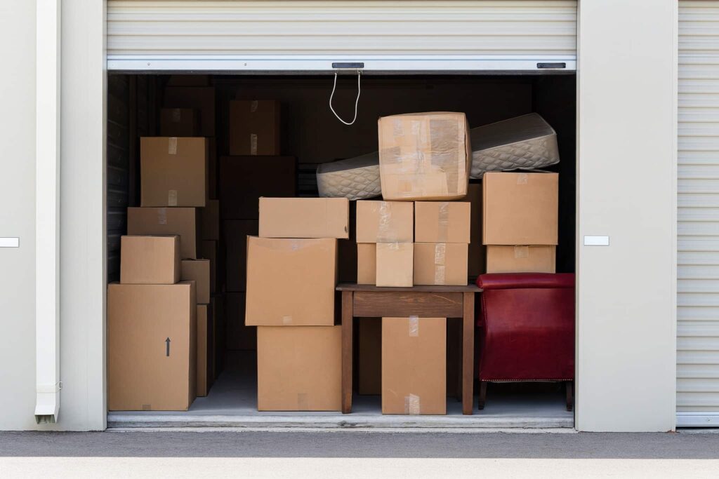 Self-storage unit filled with cardboard boxes, furniture, and belongings, representing the growing need for affordable storage solutions
