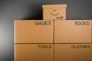 Labeled moving boxes for shoes, clothes, books, tools, and toys stacked neatly, showing organization tips for self-storage